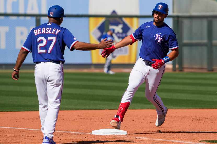 Texas Rangers first baseman Nathaniel Lowe celebrates with third base coach Tony Beasley as...
