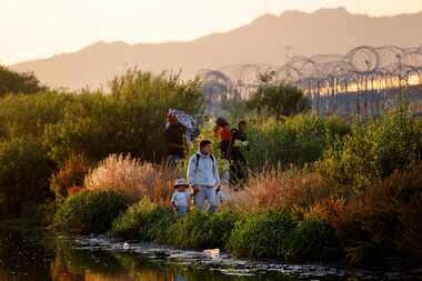 Migrant people wait behind concertina wire on the U.S. side of the Rio Grande river at Gate...
