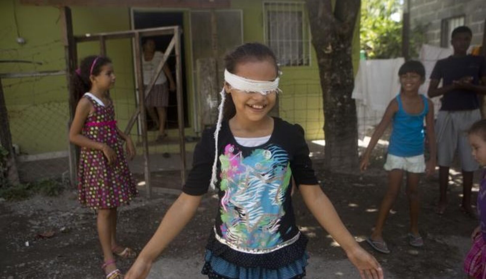 Niños juegan a la gallinita ciega en La Ceiba, Honduras. Bajo la ley, los niños hondureños,...