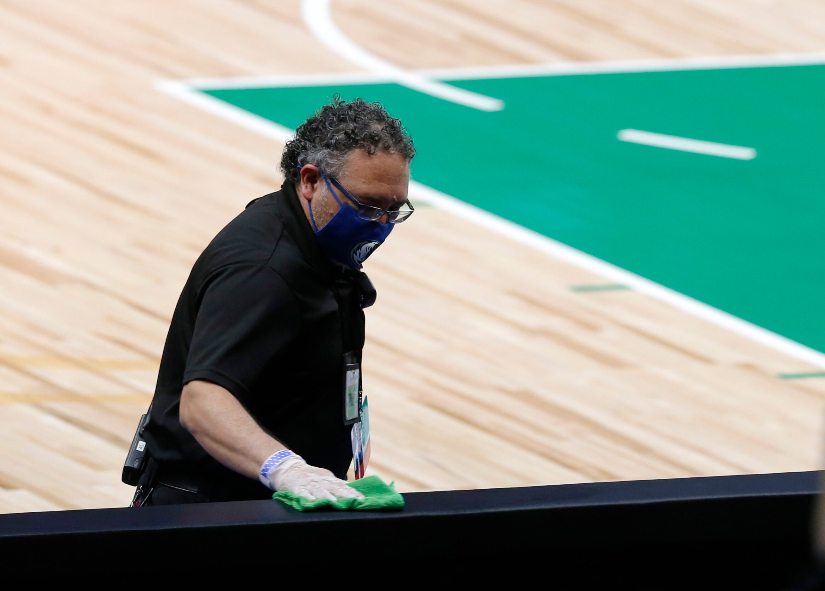 Employees clean the an area next to the court before a game between the Dallas Mavericks and...