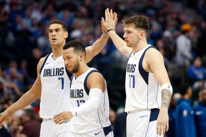 Dallas Mavericks forward Luka Doncic (77) slaps hands with forward Dwight Powell (7) as they...