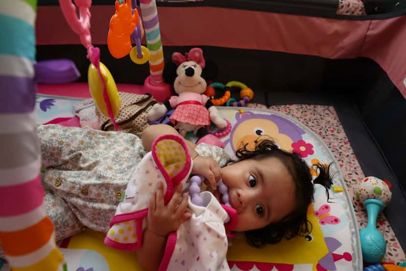 Six-month-old Selena Mendez chews on a toy while teething in her play pin on May 16, 2022,...