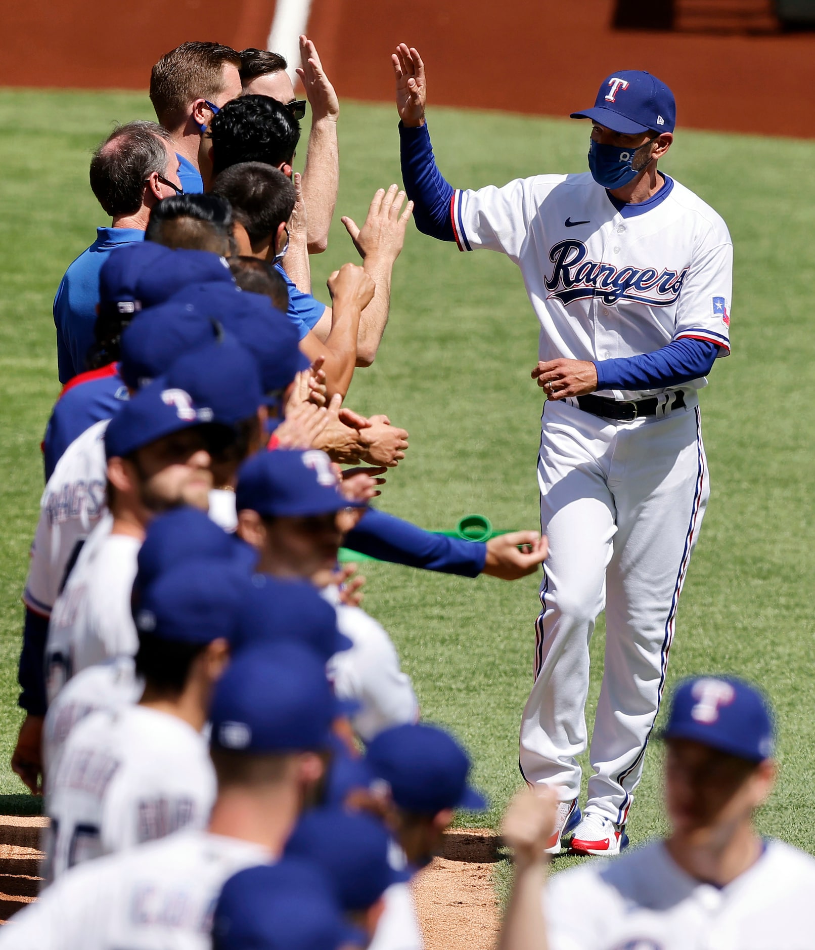 Texas Rangers manager Chris Woodward receives high-fives from his players during the team...