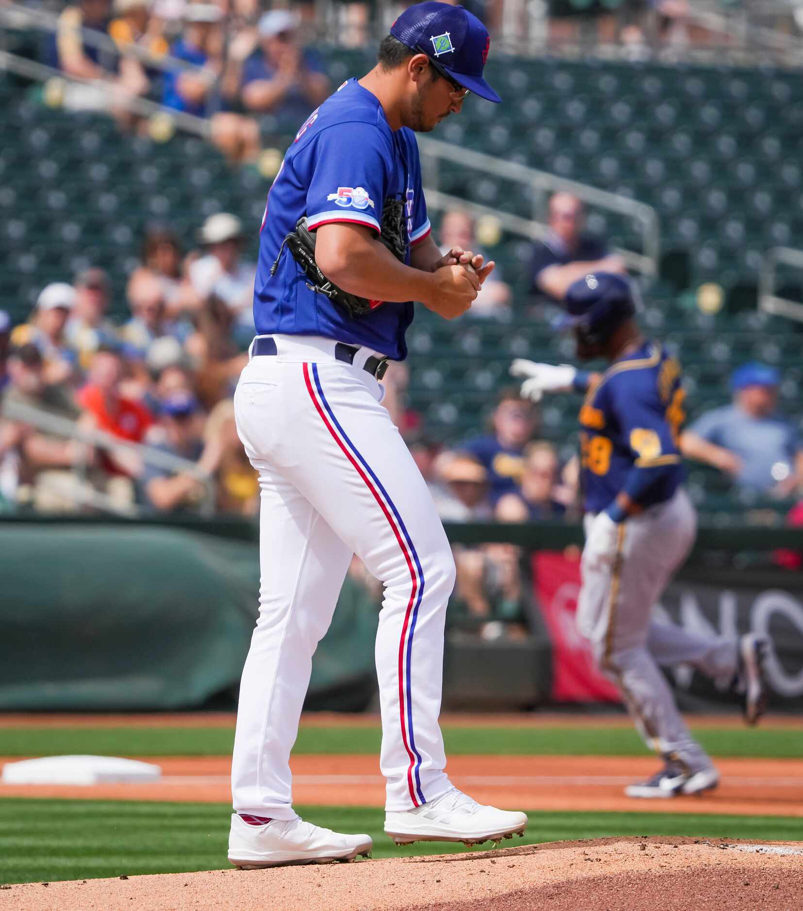 Texas Rangers pitcher Dane Dunning rubs a new ball as Milwaukee Brewers catcher Pedro...