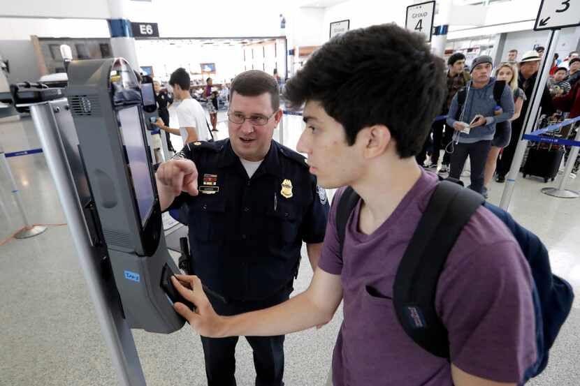 U.S. Customs and Border Protection supervisor Erik Gordon, left, helps passenger Ronan...