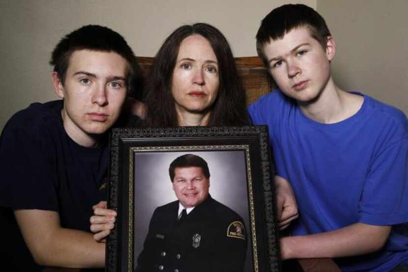 
Jenny Wilson holds a photograph of Stanley Wilson, her late husband, with her sons, Noah,...
