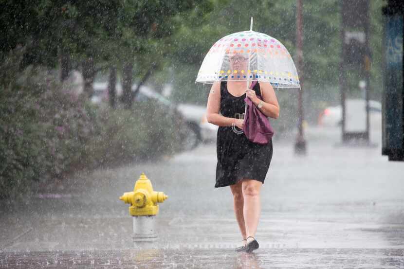 A pedestrian walks with an umbrella on the streets of downtown during Friday afternoon...