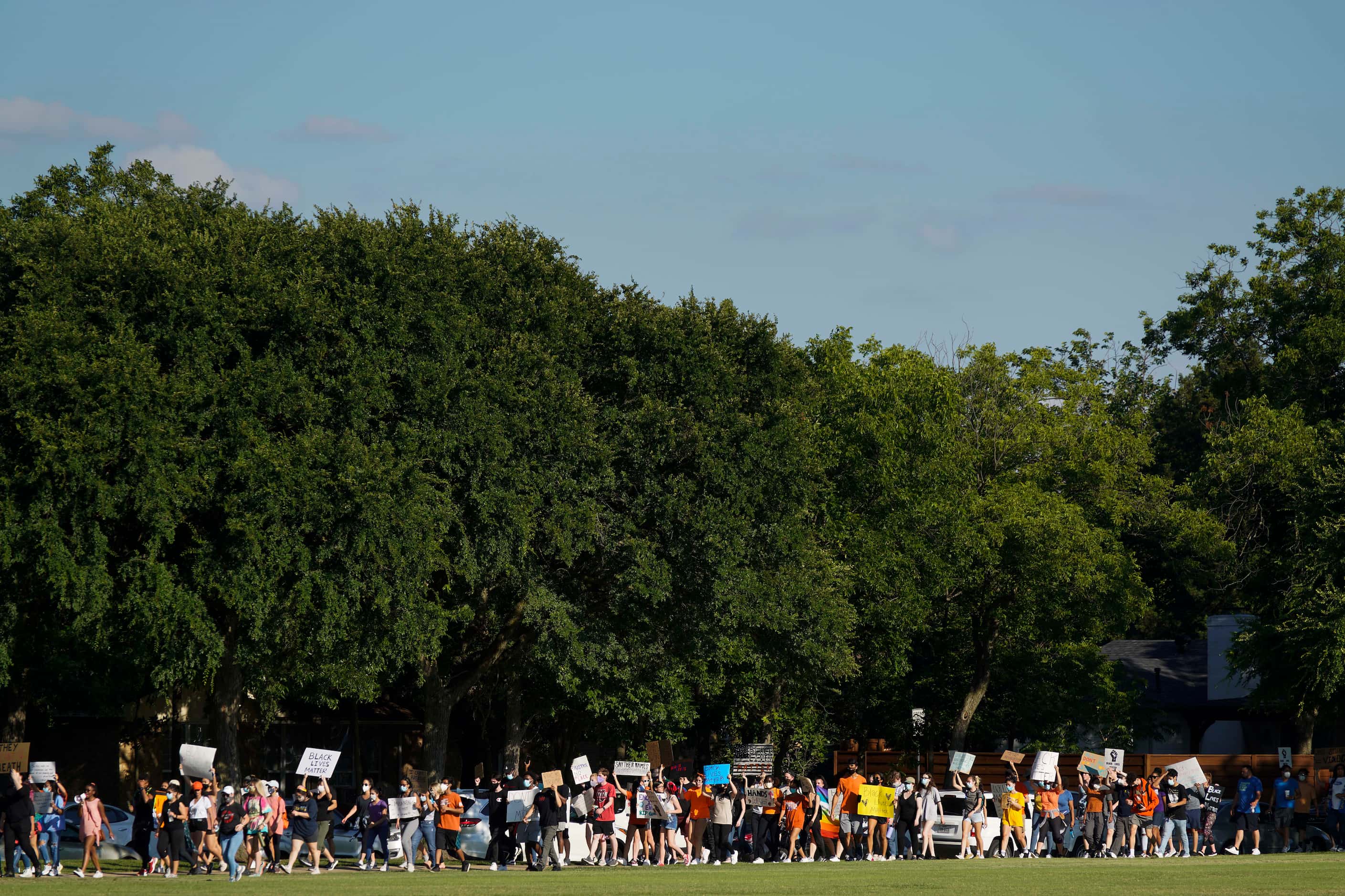 Demonstrators march around the perimeter of Berkner Park during a protest organized by...