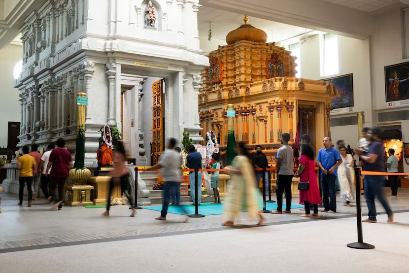 People walk around the altars of the deities in prayer at Karya Siddhi Hanuman Temple in...