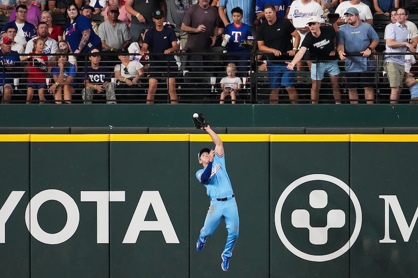 Texas Rangers outfielder Wyatt Langford (36) makes a leaping catch at the wall on a line...