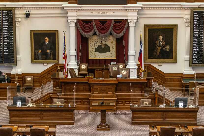 Acrylic glass barriers line certain desk areas in the House Chamber at the Texas State...