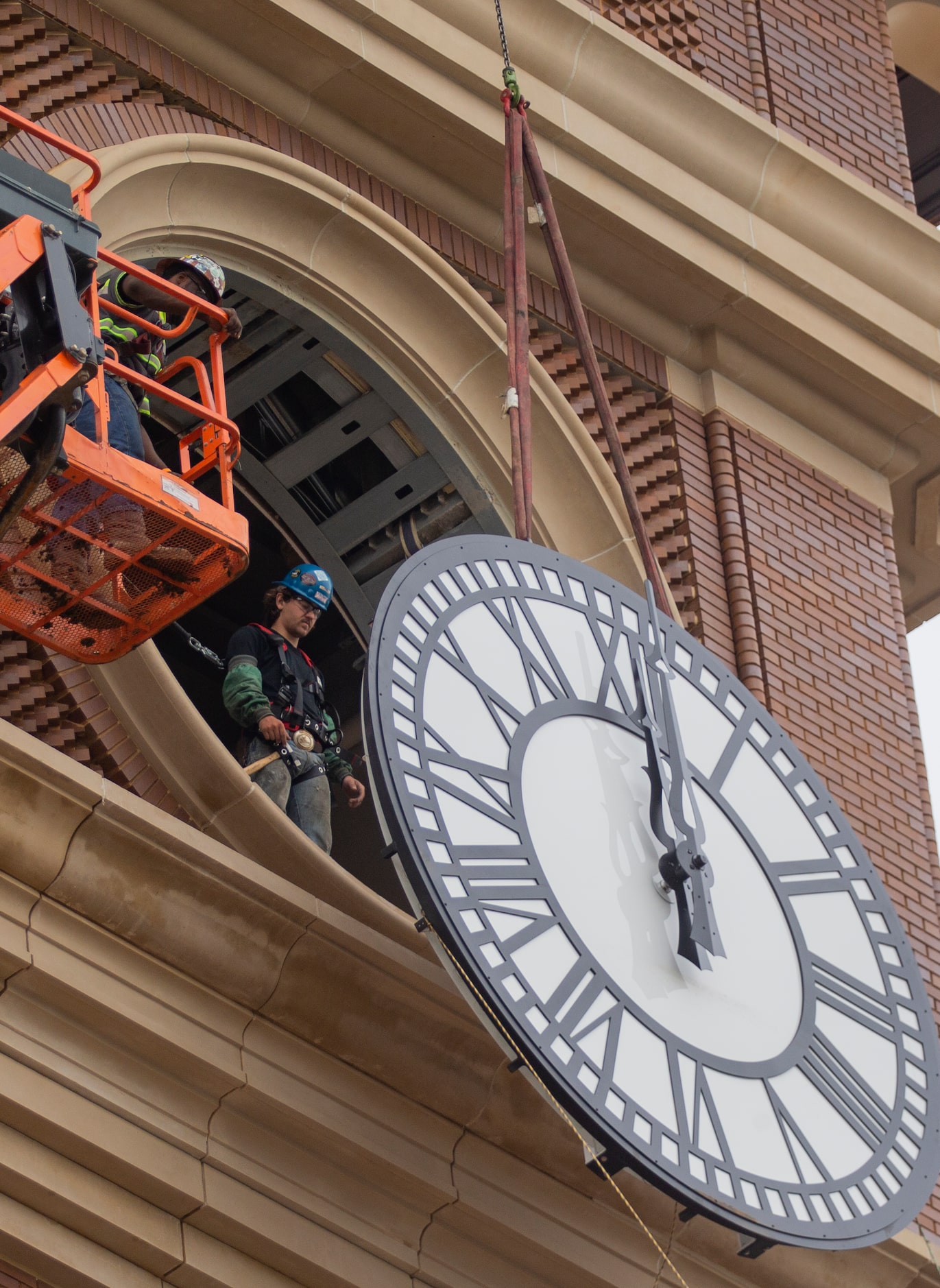 Workers from MEI Rigging & Crating work to install a 12-foot glass clock on the Grapevine...