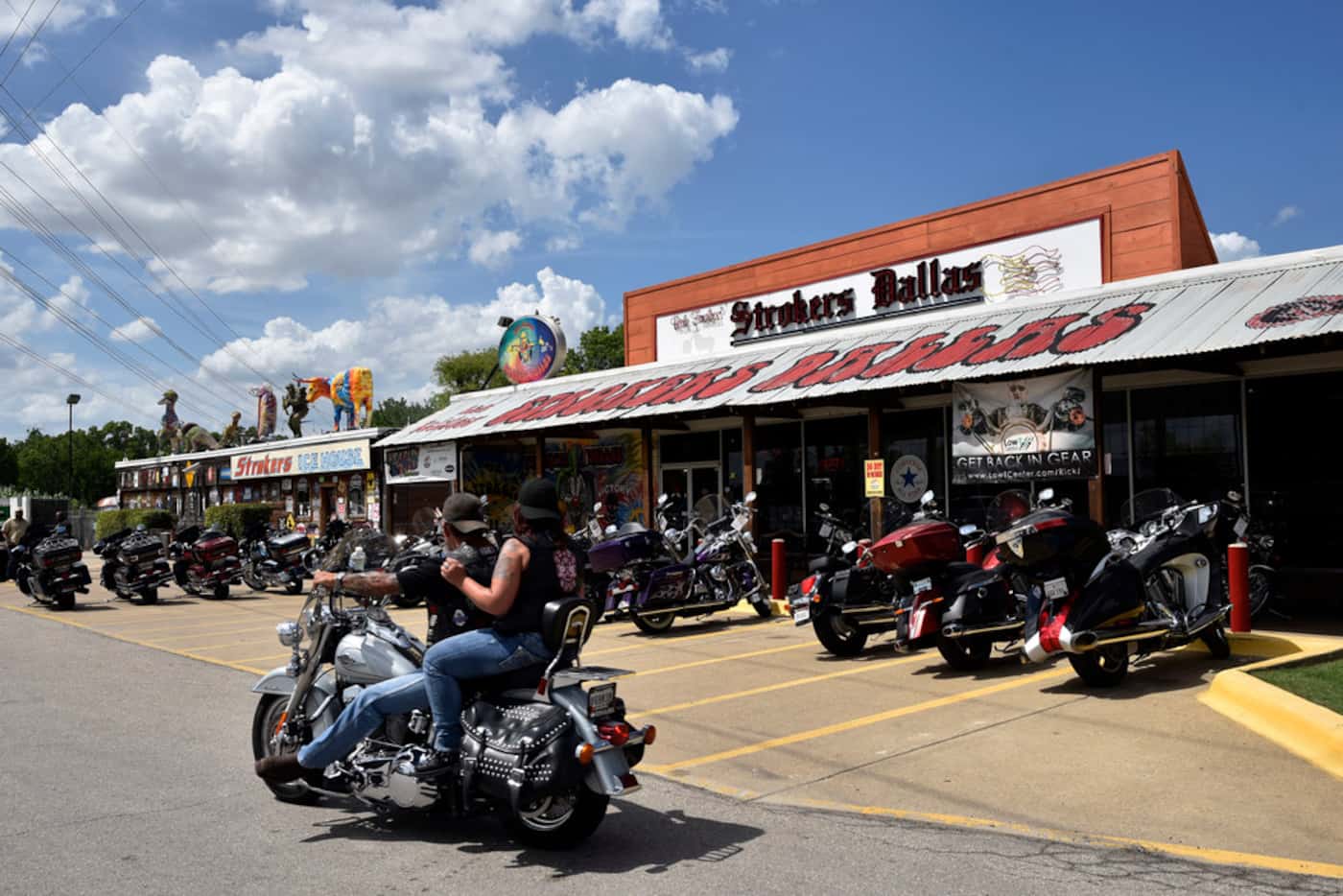 A couple ride a bike into the parking lot of Strokers Dallas, Saturday afternoon, June 16,...