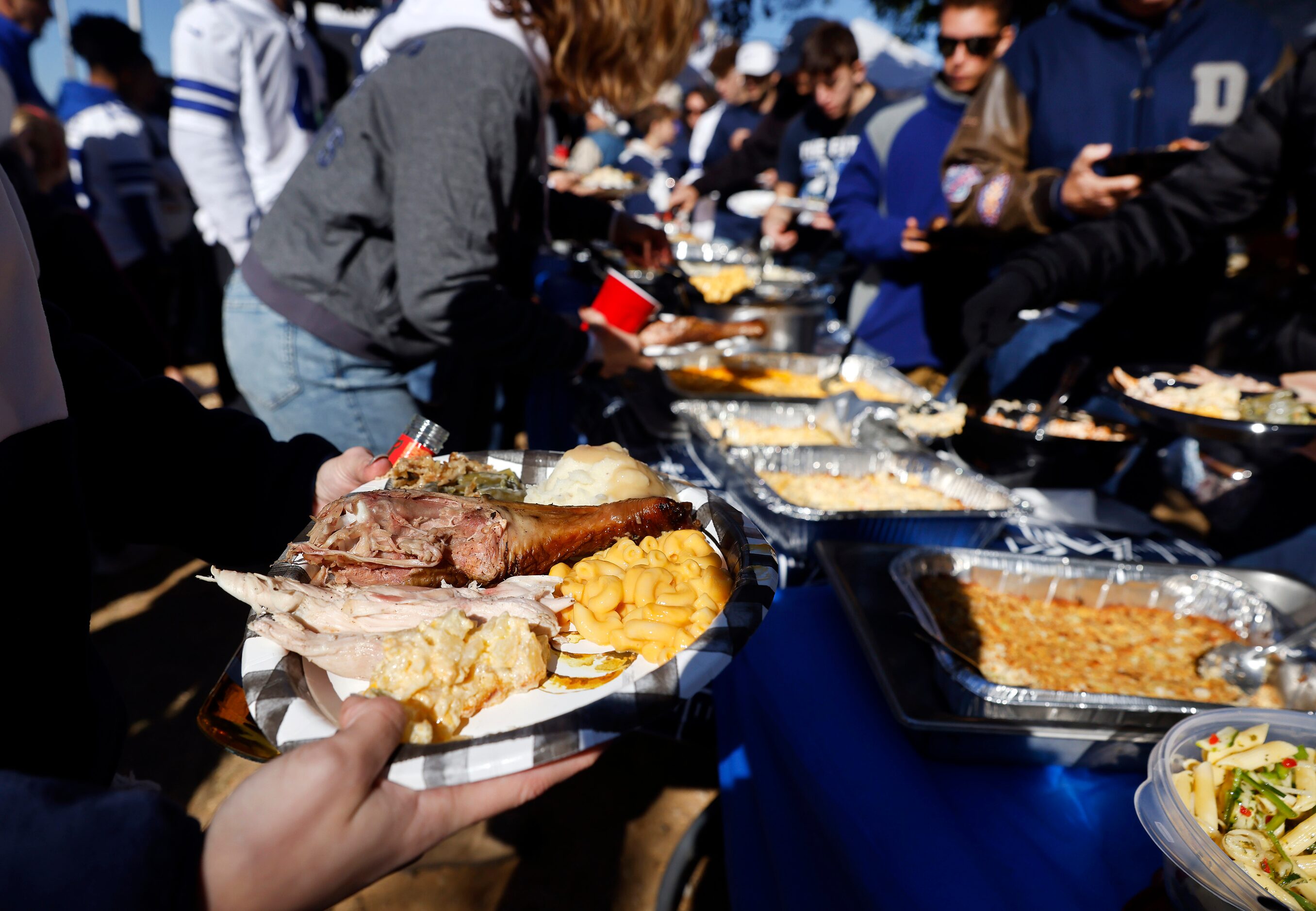 Dallas Cowboys fans dig into a Thanksgiving feast during at tailgate party outside of AT&T...