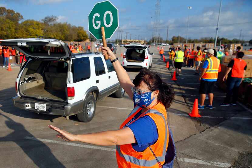 Volunteer Maria Monteverde directed traffic as vehicles pulled up for bagged fruits and...