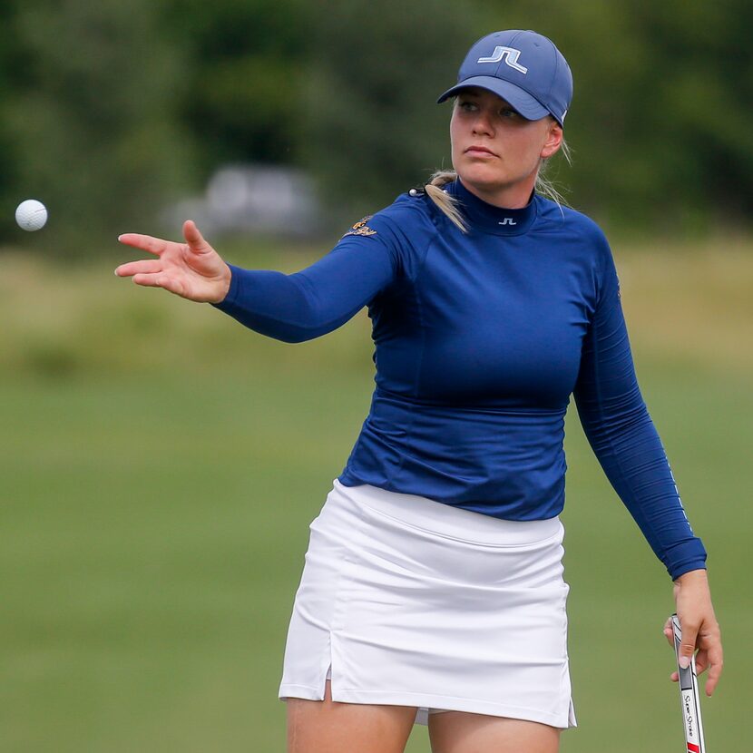 Professional golfer Matilda Castren tosses a ball to her caddie on the No. 18 green during...