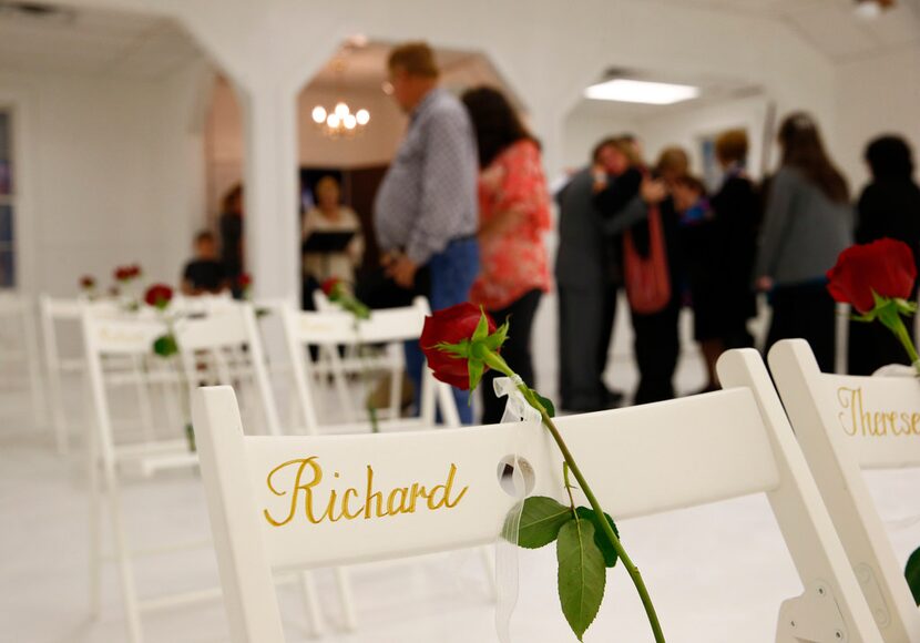 Visitors walk look at chairs and roses represented the slain as they are allowed into First...