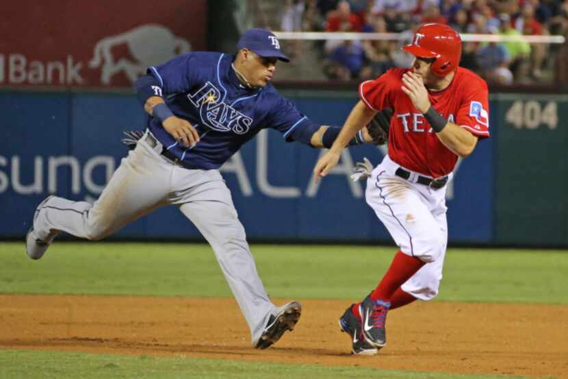 Texas second baseman Ian Kinsler is tagged out by Tampa shortstop Yunel Escobar after being...