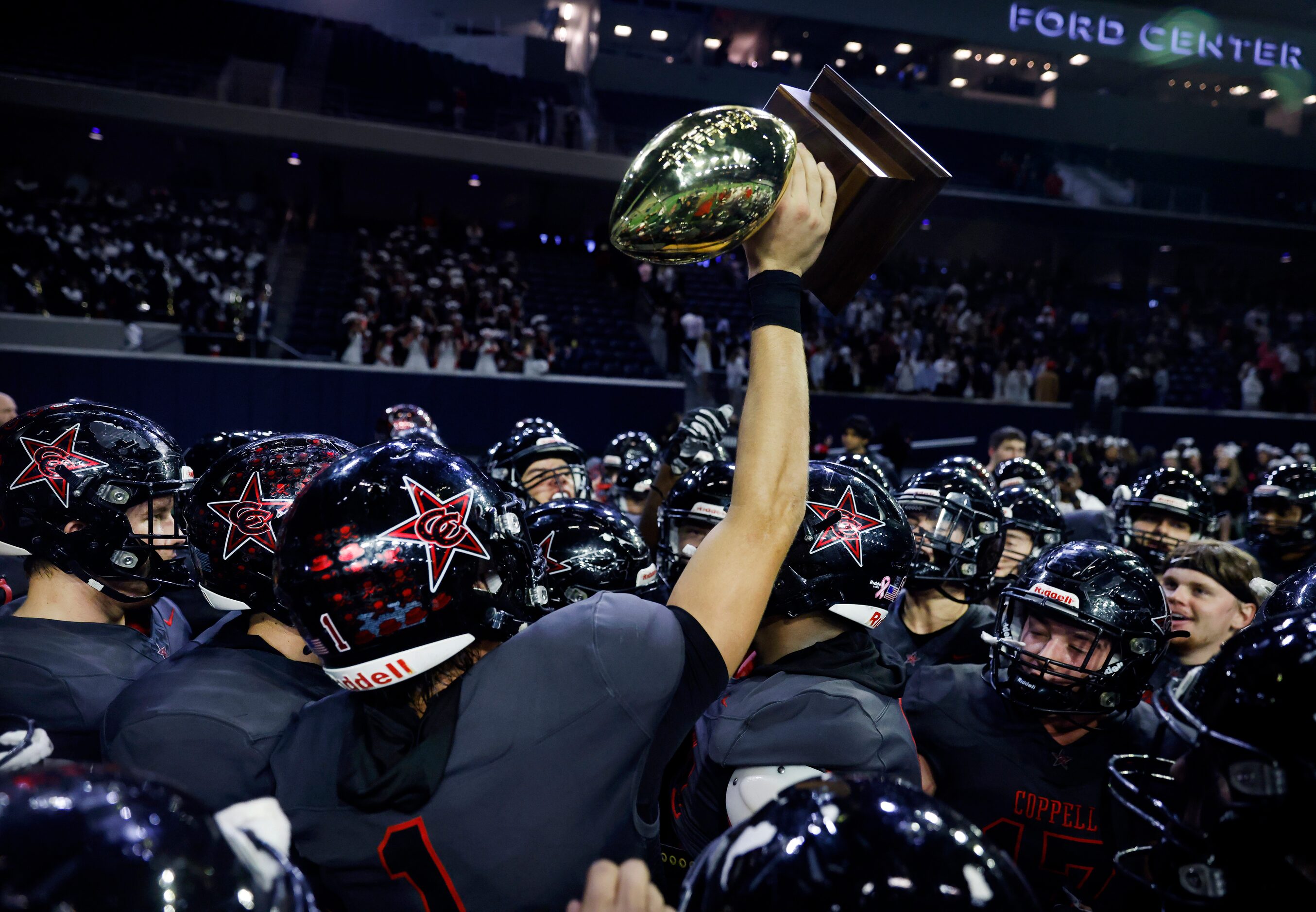 Coppell wide receiver Barton Tipton (1) hoists the Class 6A area-round playoff trophy after...