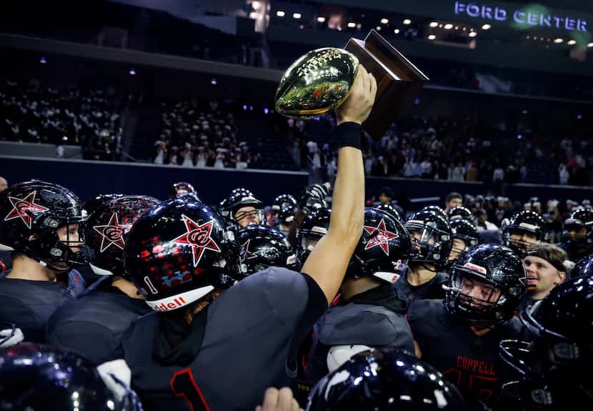 Coppell wide receiver Barton Tipton (1) hoists the Class 6A area-round playoff trophy after...