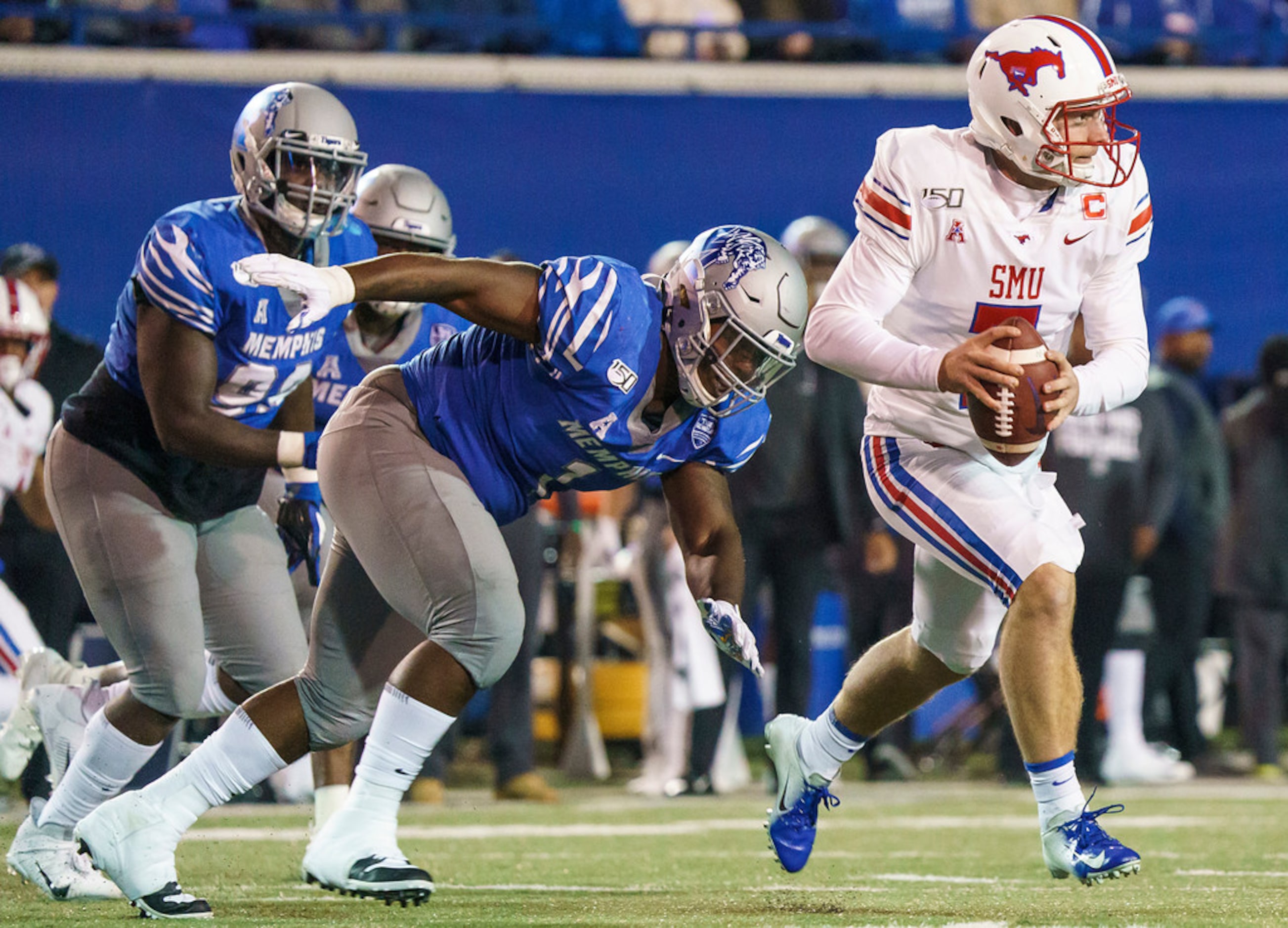 SMU quarterback Shane Buechele (7) scrambles away from Memphis defensive lineman O'Bryan...