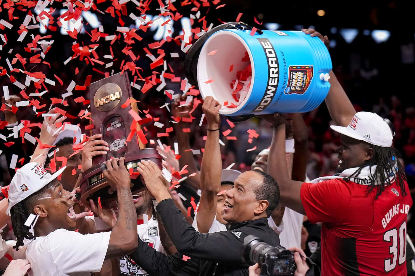 North Carolina State head coach Kevin Keatts hands the trophy to his team as forward DJ...