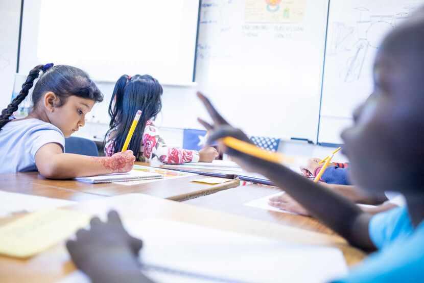 Shar Reh, 7, left, writes in her journal as Ajuda Nyabu, 7, right, concentrates during DISD...