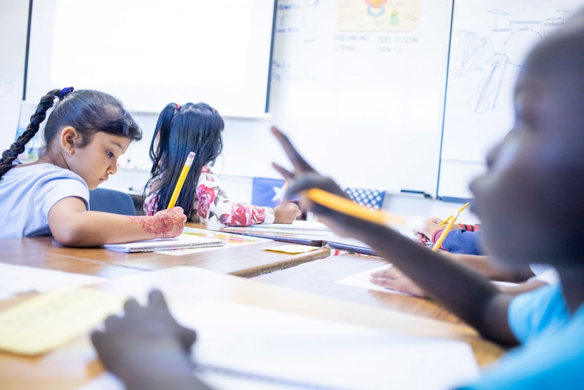 Shar Reh, 7, left, writes in her journal as Ajuda Nyabu, 7, right, concentrates during DISD...