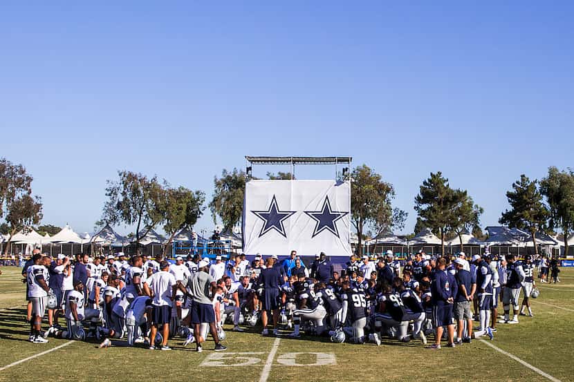 Dallas Cowboys players huddle around head coach Jason Garrett at the conclusion of afternoon...