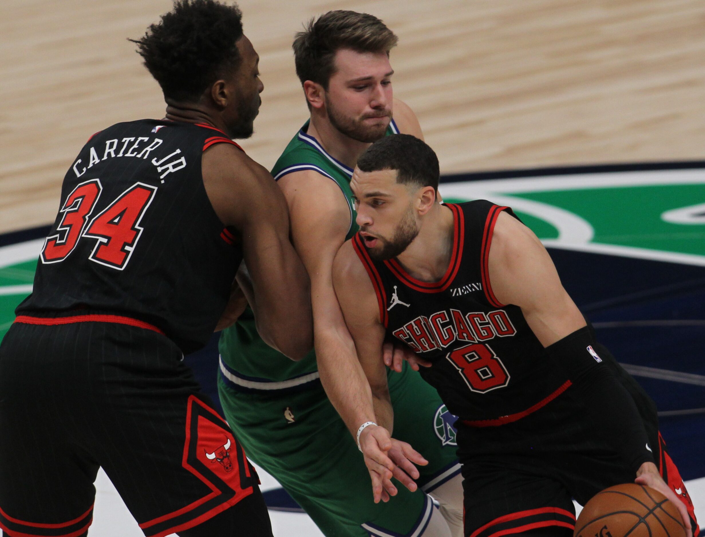 Dallas Mavericks guard Luka Doncic (77) grimaces as his right arm is pinned between Chicago...