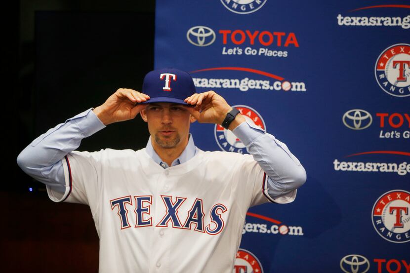 New Texas Rangers pitcher Mike Minor puts on a team cap before a press conference at Globe...