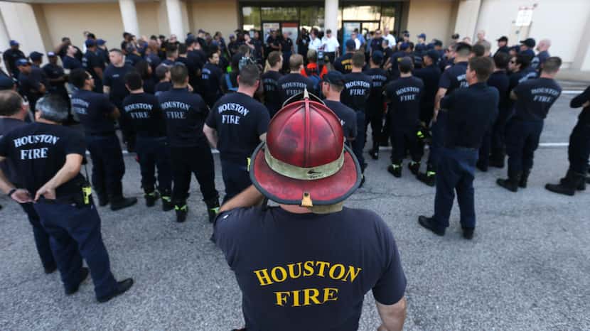 Houston firefighters gather for a briefing before going on a door-to-door survey of a...