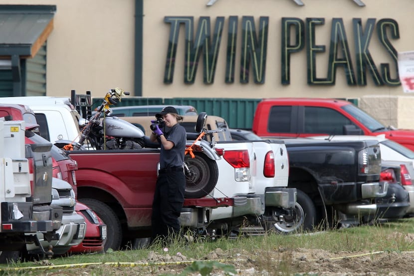 A law enforcement officer photographs a vehicle in the rear parking lot of a Twin Peaks...