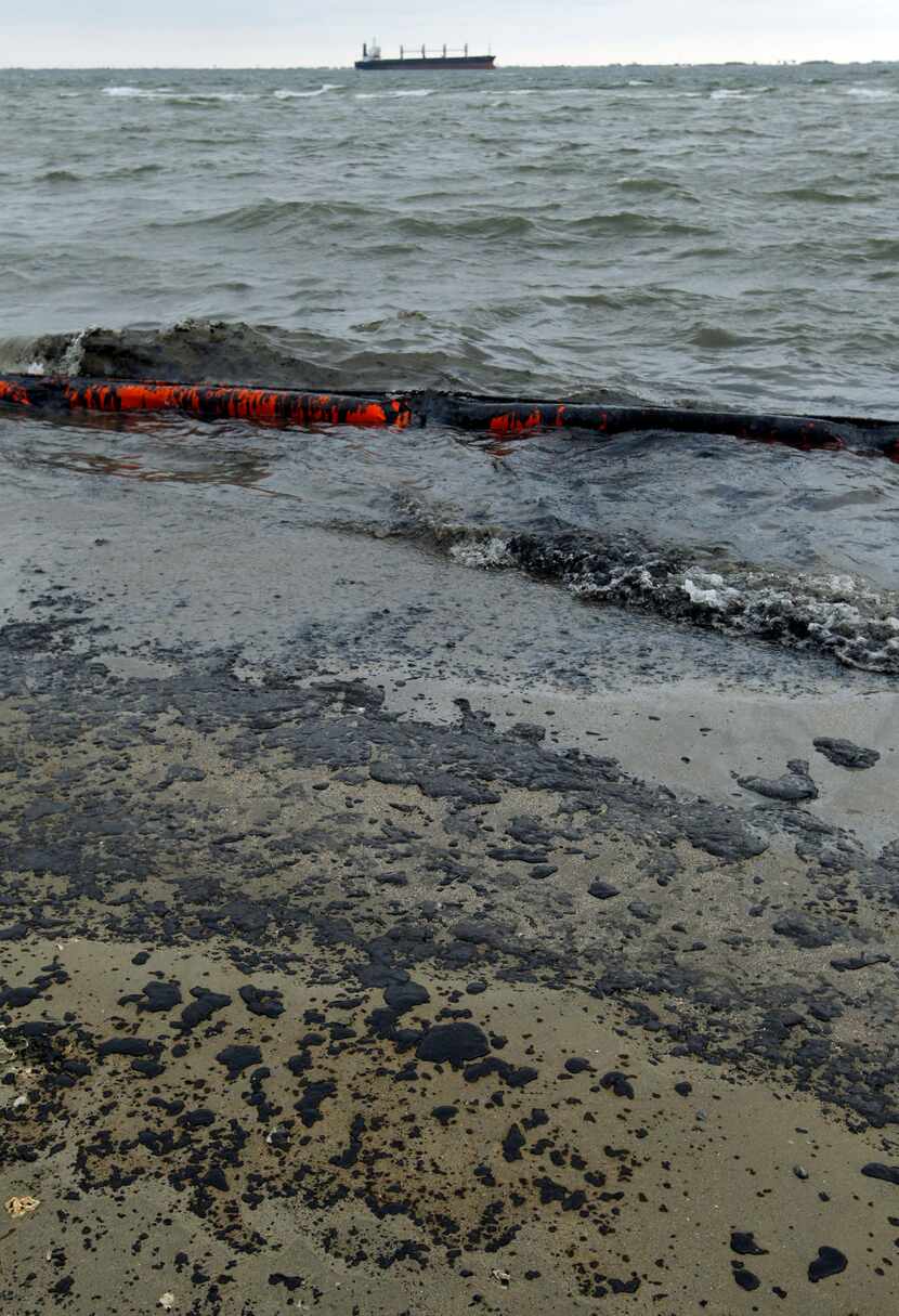 Heavy crude oil washes over booms and onto the beach along Boddeker Road in Galveston.