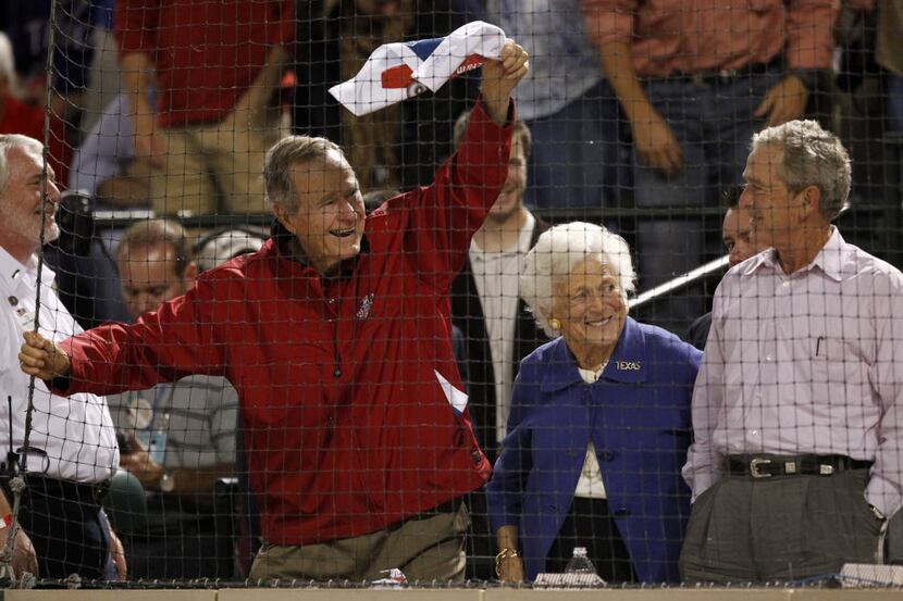 Former President George H.W. Bush waves a towel as wife Barbara and son George W. Bush look...