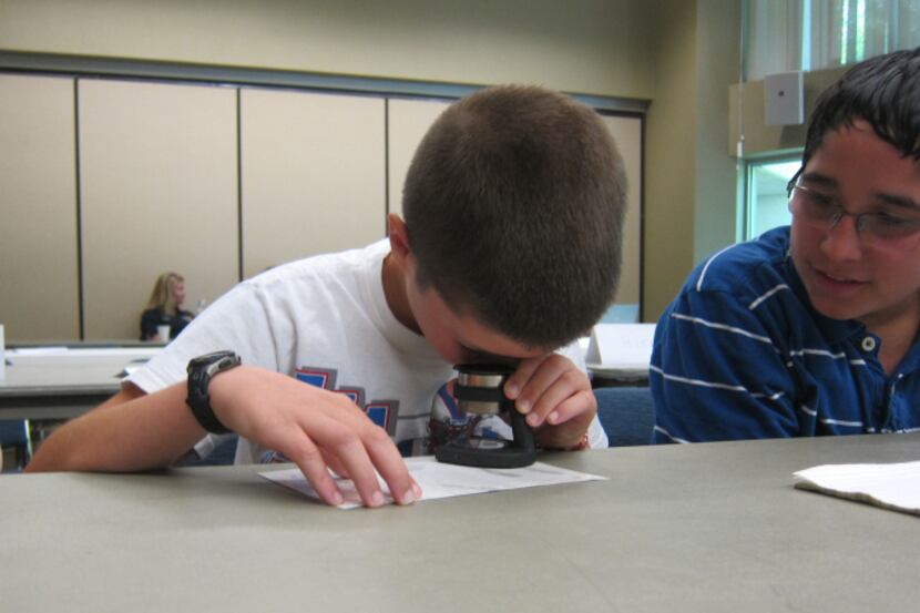 Isaiah Tovar,13,  looks on as Trenton Turek, 10, examines a finger print taken from a window...