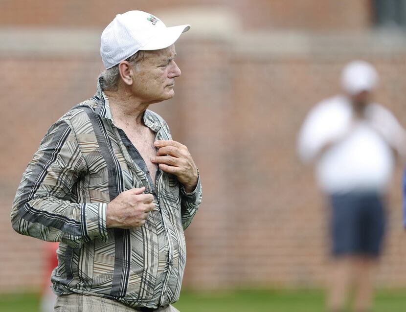 Actor Bill Murray unbuttons his shirt and celebrates after hitting a putt on the 16th hole...