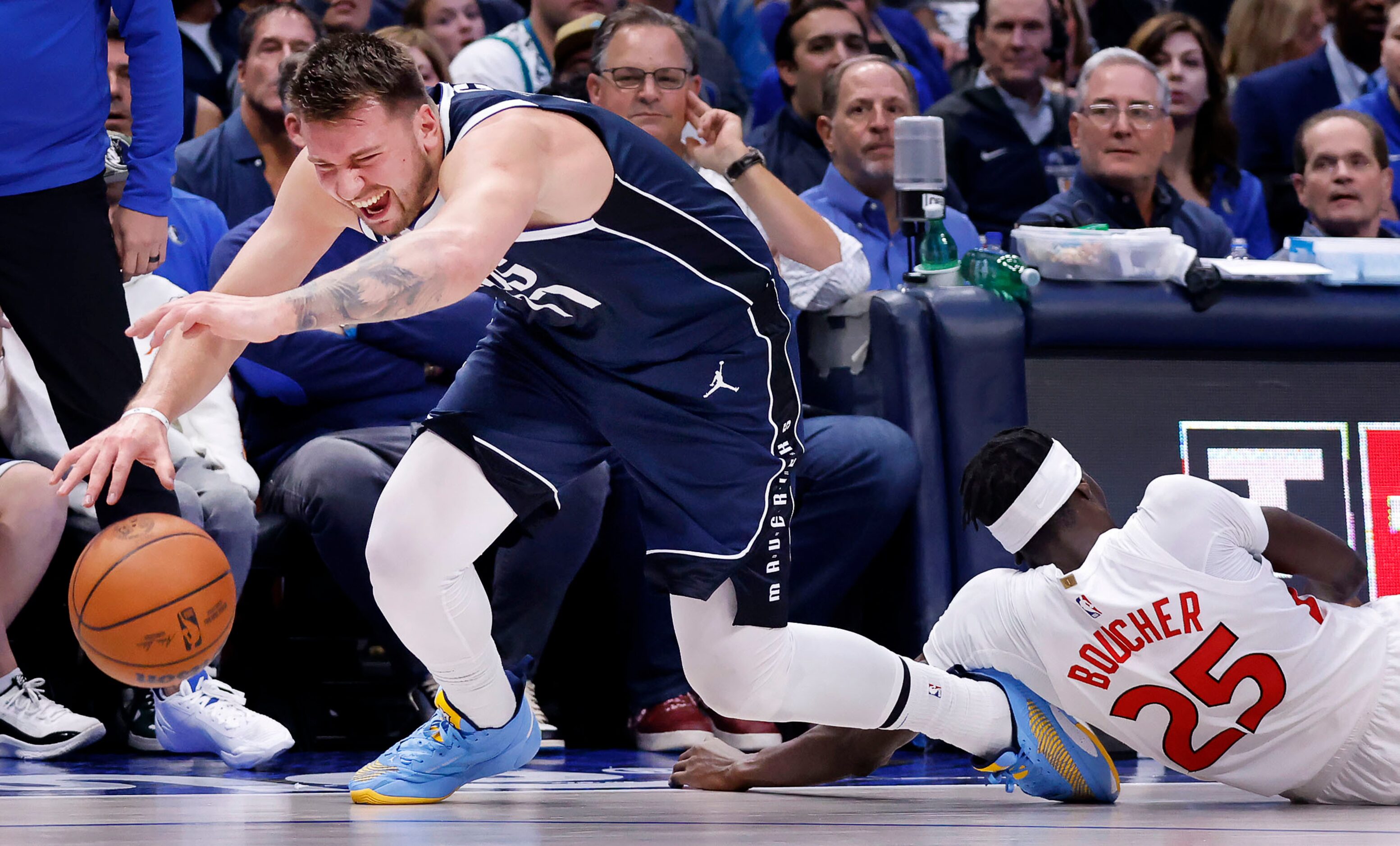 Dallas Mavericks guard Luka Doncic (77) gets his foot caught under Toronto Raptors forward...