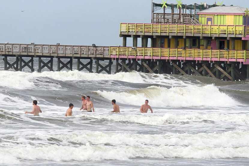 
Beachgoers waded into the rough surf Monday near the 61st Street Fishing Pier in Galveston...