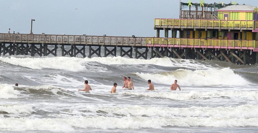 
Beachgoers waded into the rough surf Monday near the 61st Street Fishing Pier in Galveston...