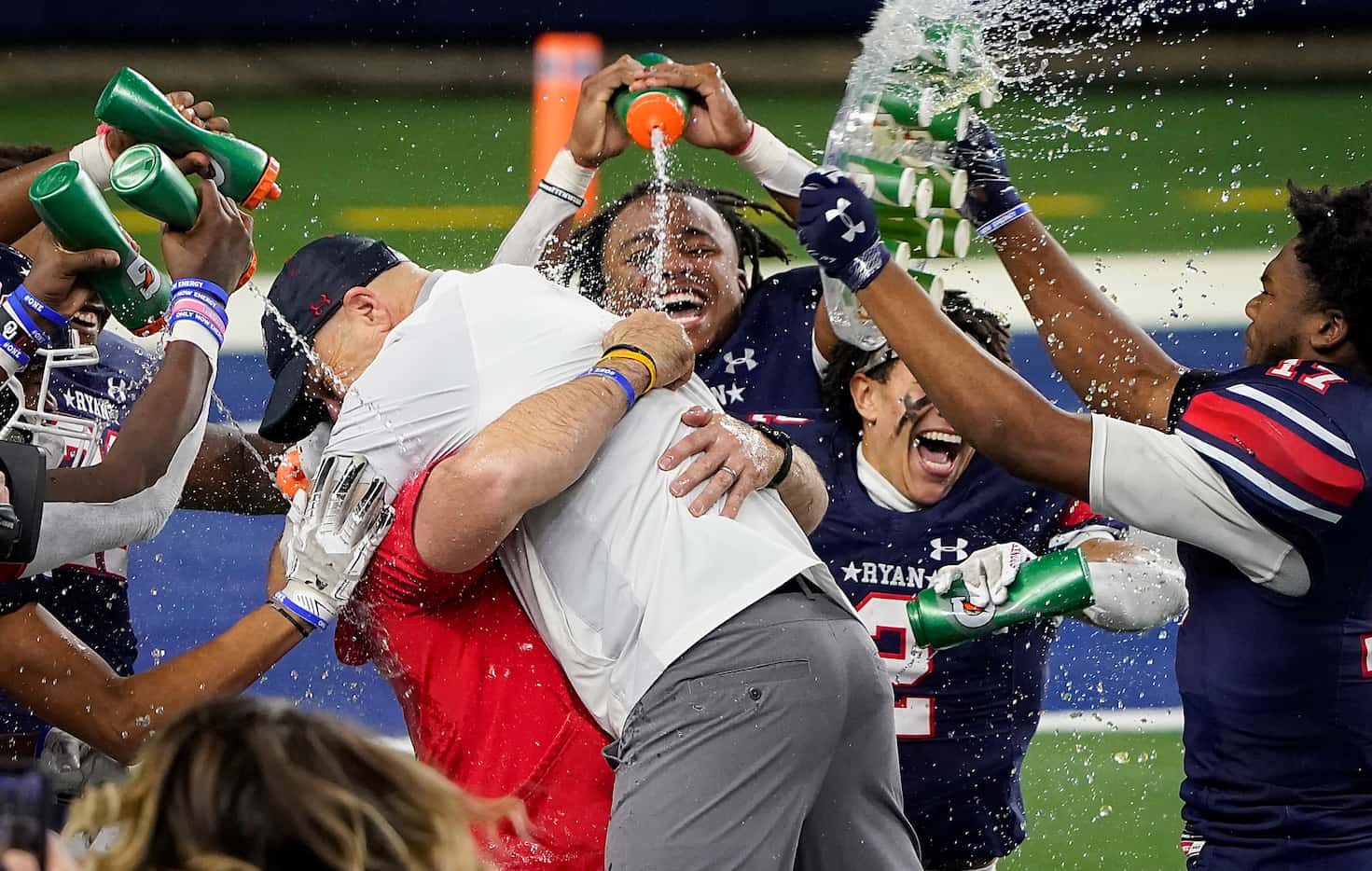 Denton Ryan head coach Dave Henigan hugs assistant coach Shane Tolleson as they are doused...