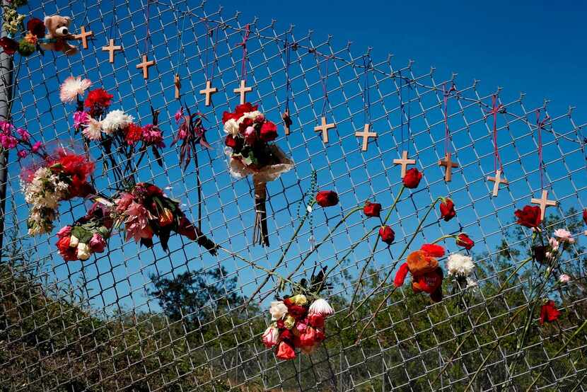 Flowers and crosses line a fence near the school on a makeshift memorial for the victims of...