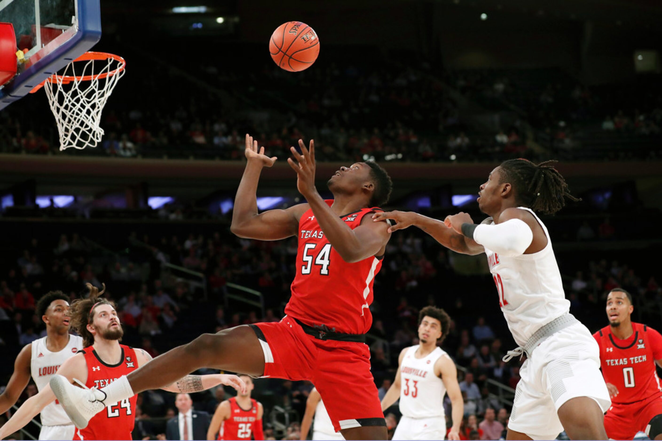 Texas Tech center Russel Tchewa (54) looks to grab the ball as Louisville forward Aidan...