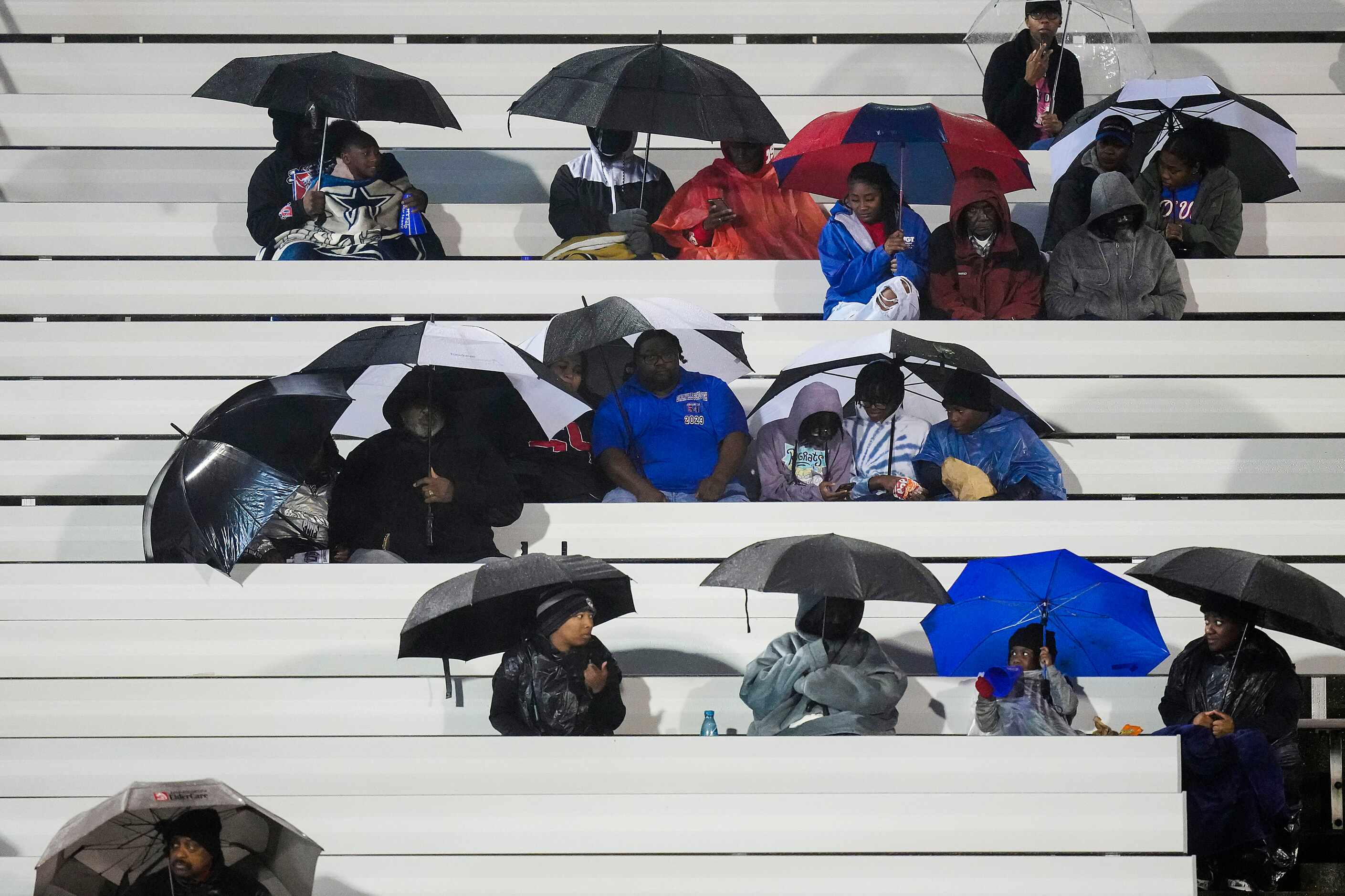 Duncanville fans take cover from a cold rain before a District 11-6A high school football...