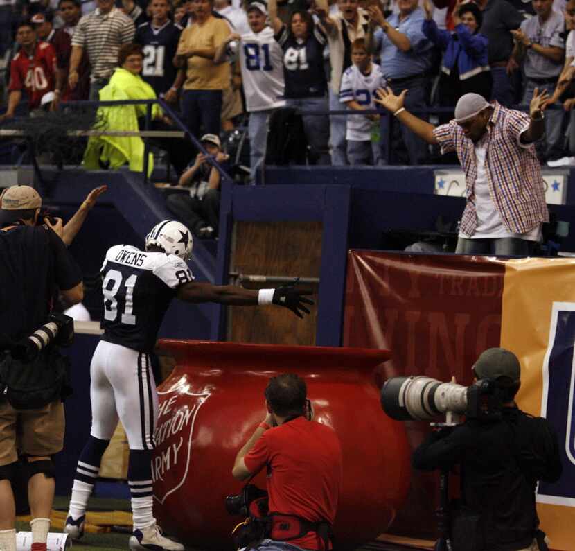 Dallas WR Terrell Owens drops the ball into the Salvation Army pot after catching a 3rd...