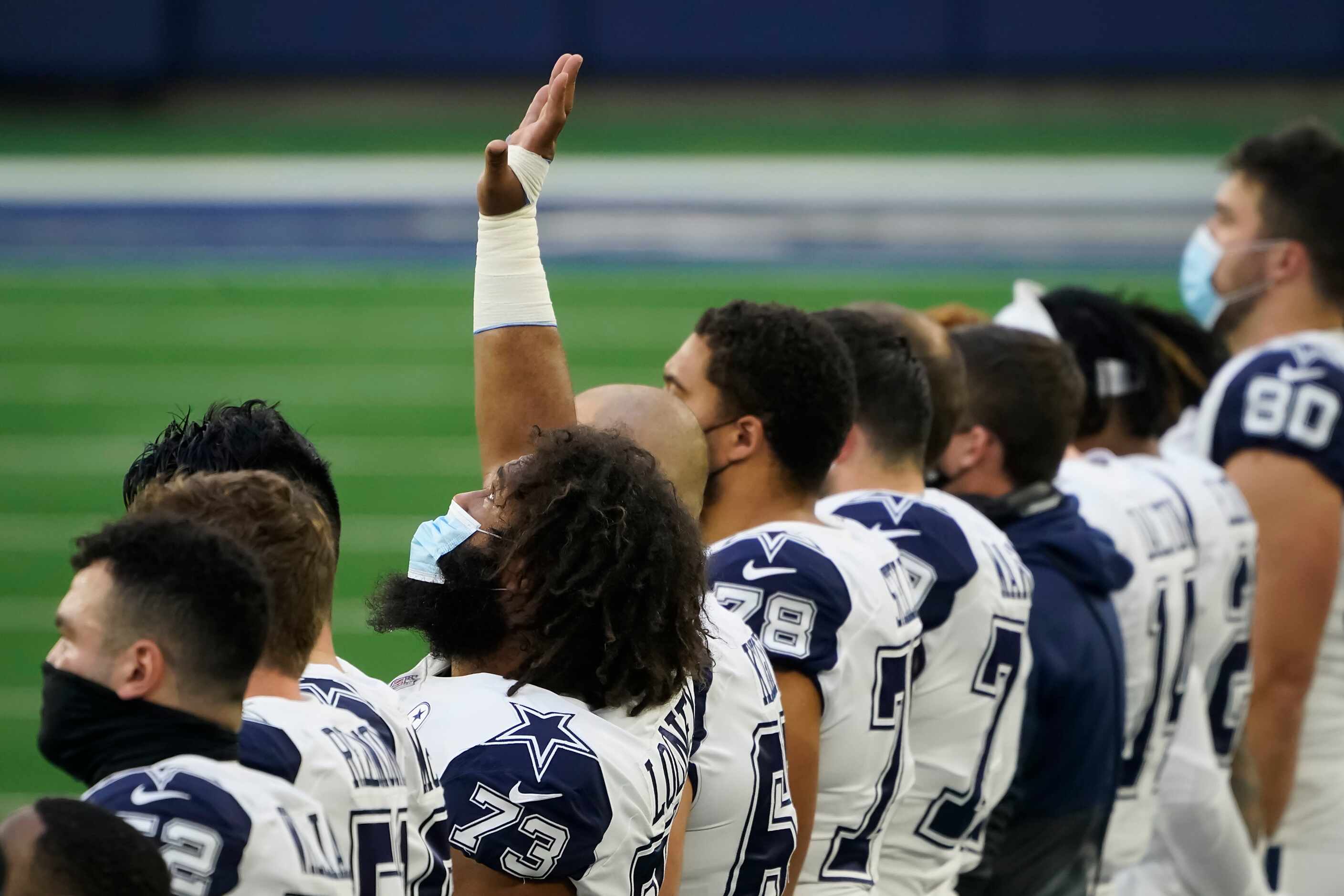 Dallas Cowboys center Joe Looney looks upward with his hand in the air during the national...