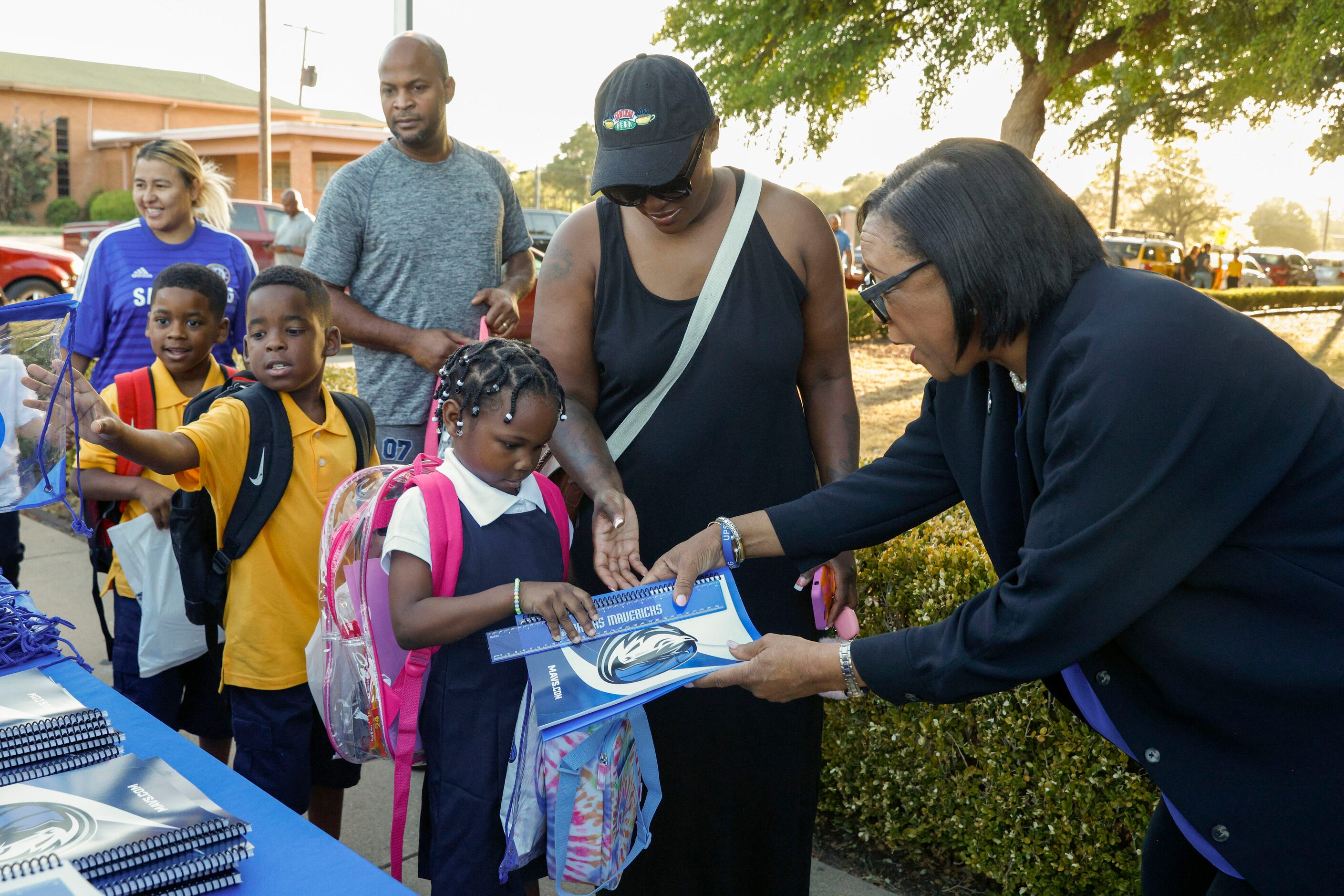 Dallas Mavericks CEO Cynt Marshall (right) hands Amberly T., 6, a Mavs notebook and ruler...