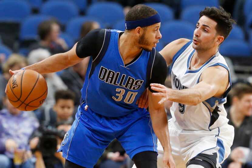 Dallas Mavericks' Seth Curry, left, keeps the ball at a safe distance from Minnesota...