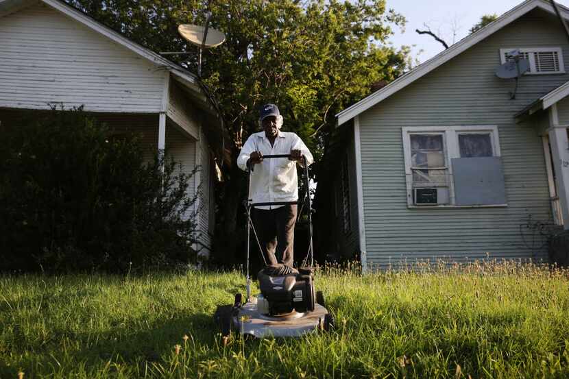 Leroy Bee mows the lawn of a house along 9th Street on the east side of Interstate 35 in the...