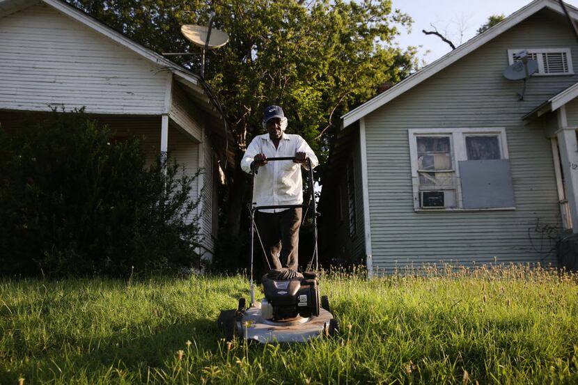 Leroy Bee mows the lawn of a house along 9th Street on the east side of Interstate 35 in the...